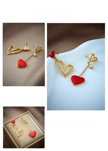 Detail of asymmetrical heart drop earrings with red enamel and gold hollow frames