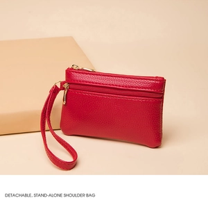 Detail of red pebbled leather coin purse with double gold zippers and wrist strap