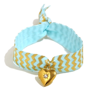 Blue ribbon bracelet with gold wavy patterns and a heart locket pendant with zircon