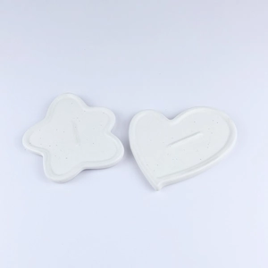 Detail of white ceramic heart and flower jewelry trays with subtle textured finish