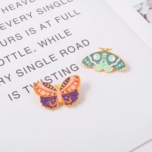 Celestial butterfly and moth enamel pins with moon and star patterns on white card