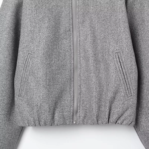 Detail view of gray pilot jacket fabric texture with silver zipper and side pockets