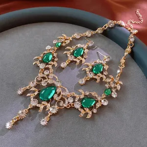 Vintage gold-tone jewelry set with green teardrop gemstones and vine leaves