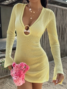 Detail of yellow crochet long sleeve dress with V-neck and golden ring ornament
