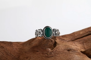 Close-up of vintage S925 silver ring with green malachite stone and floral motifs on wood