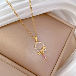 Close-up of gold chain necklace with pink pear-cut zircon and paved ring pendant