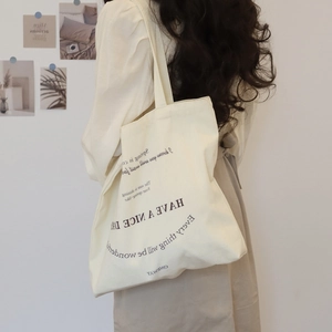 Minimalist cream canvas tote bag with black typography print shown on a model