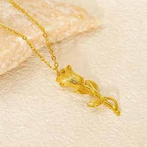 Détail d'un pendentif rose en acier inoxydable doré posé sur une surface en pierre
