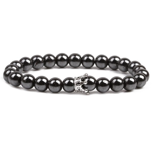 Close-up of black beaded stone bracelet featuring a silver crown charm on white background