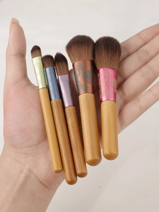 Macro detail of 5-piece mini makeup brushes with wooden handles and colorful floral ferrules