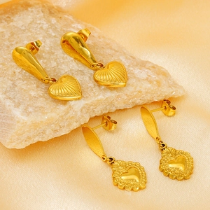 Détail de boucles d'oreilles cœur dorées sur pierre avec tissu en soie élégant
