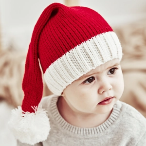 Detailed close-up of a baby wearing a cozy red and white Christmas knit hat with pom-pom