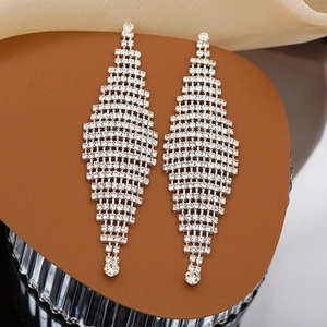 Close-up of geometric long tassel drop earrings with silver rhinestones on warm background