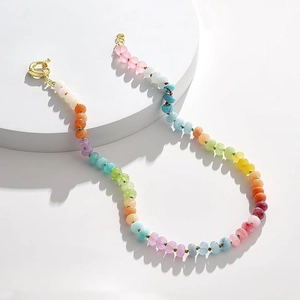 Detail of colorful bohemian stone bead necklace with a gold spring ring clasp on white