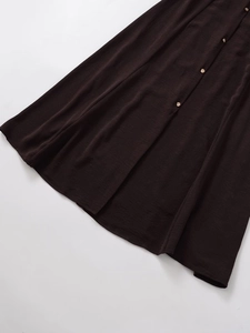 Detalle de vestido de verano marrón oscuro con textura de tela fina y botones de metal