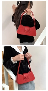 Detail view of red baguette underarm bag with bow decoration on a shoulder strap