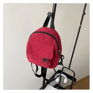 Detail of red corduroy backpack texture with a front pocket and black D-ring buckle