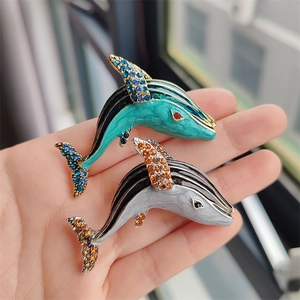 Detail of whale brooches with enamel finish and sparkling rhinestones on hand