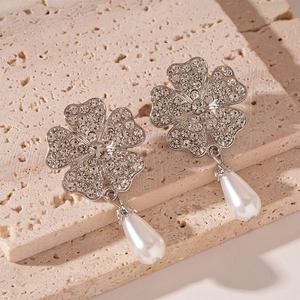 Detail of silver flower earrings with sparkling rhinestones and teardrop pearl pendants
