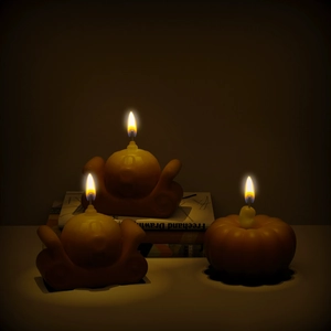 Trois bougies citrouilles d'Halloween allumées orange chaud sur table blanche et livres