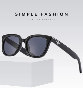 Detail of black square sunglasses featuring a star metal accent on minimalist stand