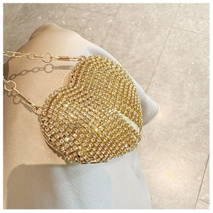 Detail of a gold heart-shaped mini evening bag with sparkling rhinestones and chain strap