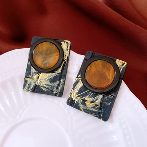 Close-up of vintage resin square leather earrings with amber stones on white porcelain