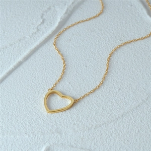 Close-up of golden minimalist heart pendant necklace on white textured background
