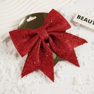 Detail einer roten Glitzerschleife auf weißem Schneehintergrund für Weihnachtsbaumdekor