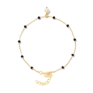 Detailed shot of a gold chain bracelet with black beads and a single white pearl pendant