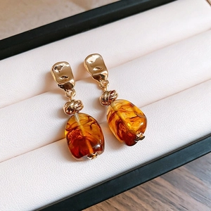 Macro shot of retro brown resin beads and gold textured knots on luxury drop earrings