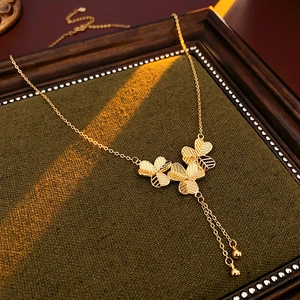 Detailed macro of gold-plated clover necklace with elegant flower tassel on green velvet