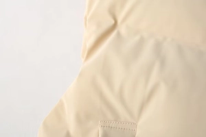 Detail of beige quilted fabric with precision stitching on a women stand collar vest