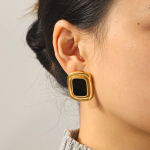 Close-up of vintage geometric gold earrings with black rectangular inlay on model