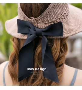 Detail of elegant straw sun hat featuring a large black ribbon bow on back
