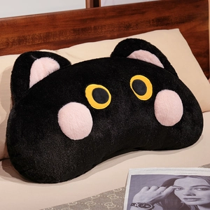Detail of soft black cat plush pillow with yellow eyes on a cozy bedroom bed