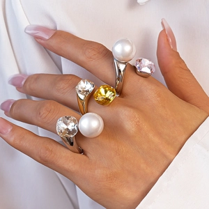 Detail of square crystals and pearls on adjustable silver and gold rings worn by a model