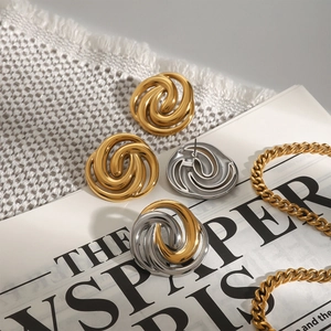 Detailed shot of polished gold and silver spiral stud earrings on vintage paper and fabric