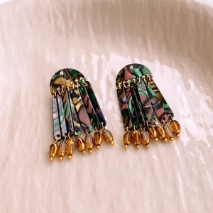 Macro view of retro acrylic tassel earrings with marbled texture on a ceramic plate