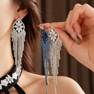 Close-up of sparkling rhombic zircon tassel earrings in silver and blue stones