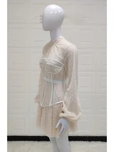 Detail of puffed mesh sleeves and white lace corset on a beige polka dot mini dress