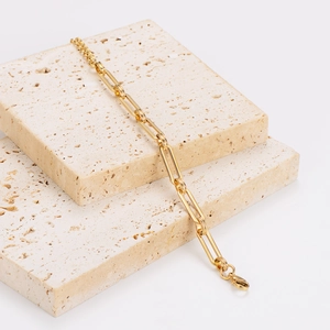 Golden stainless steel paperclip link chain bracelet displayed on stone background