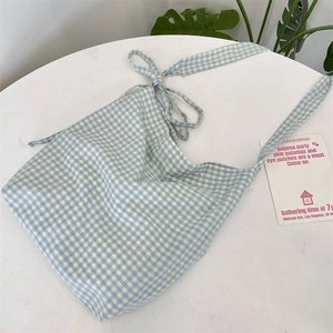 Close-up of blue and white checkered canvas tote with decorative knot shoulder strap