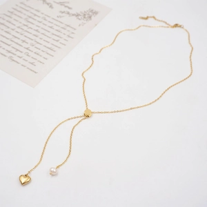 Minimalist Y-shaped golden necklace with heart pendant and pearl on white background