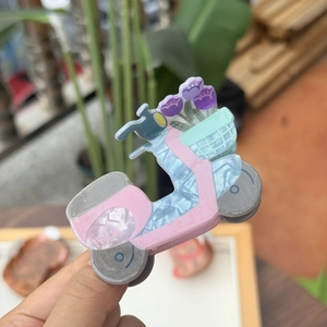Gros plan d'une pince à cheveux en acrylique bleu en forme de scooter de dessin animé