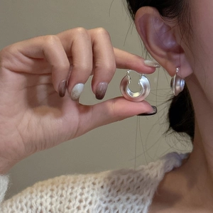 Minimalist matte silver S925 sterling silver hoop earrings worn by a model in soft light