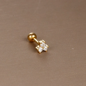 Detail of gold cartilage stud featuring three white zircons and a secure screw ball back