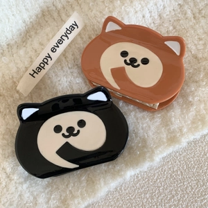 Cute dog-shaped acetate hair claws in black and caramel colors on a plush background