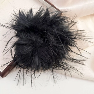 Detail of a large black faux fur scrunchie on silk background with soft lighting