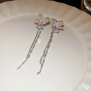 Close-up of sparkling zircon butterfly earrings with long fringe tassels in silver finish
